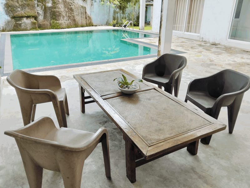 Poolside table and chairs on the covered terrace beside the pool at Villa Idda