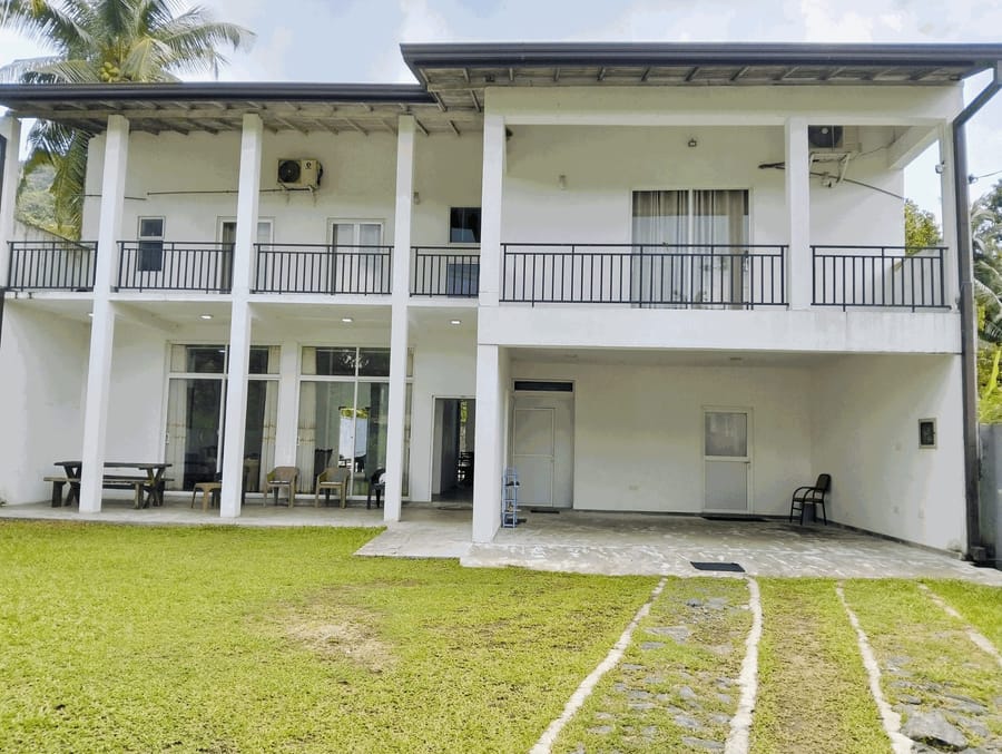 Villa Idda's two-storey white villa seen from the garden lawn, with balconies on both floors