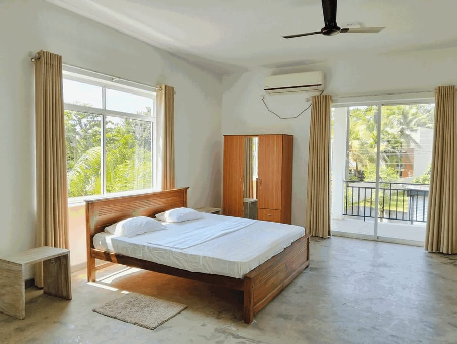 Bright double room at Villa Idda with a wooden bed, wardrobe, air conditioning and a balcony over the treetops