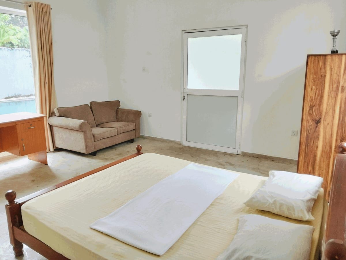 Deluxe room at Villa Idda with a double bed, sofa and a doorway onto the pool terrace